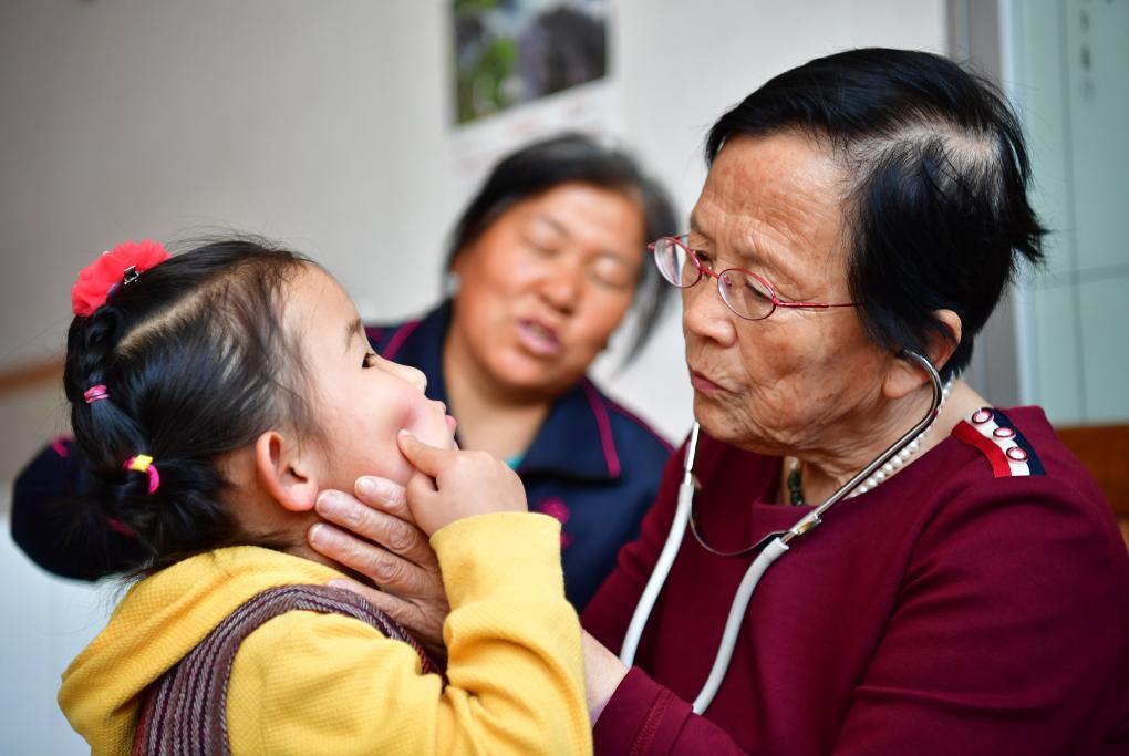 2018年4月29日，路生梅（右一）在家中給一名小朋友看病。新華社記者 邵瑞 攝